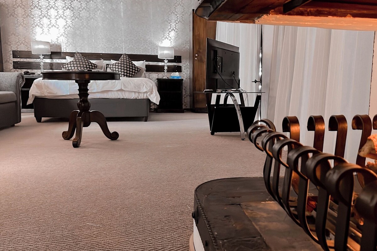 Une chambre d’hôtel avec un lit, un bureau, une chaise et une cheminée.