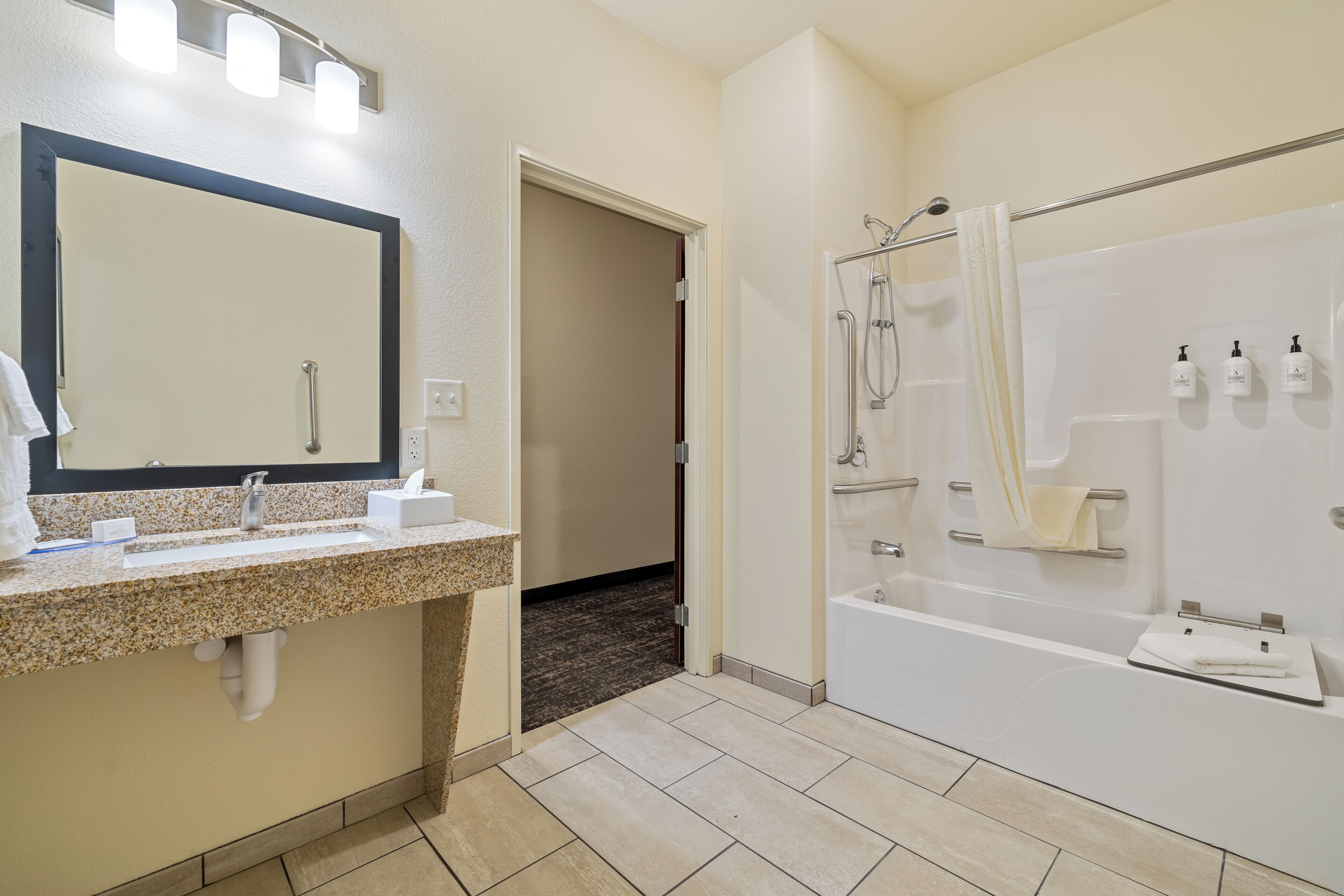 A modern bathroom with a granite countertop sink, a large mirror, a bathtub, and a shower.