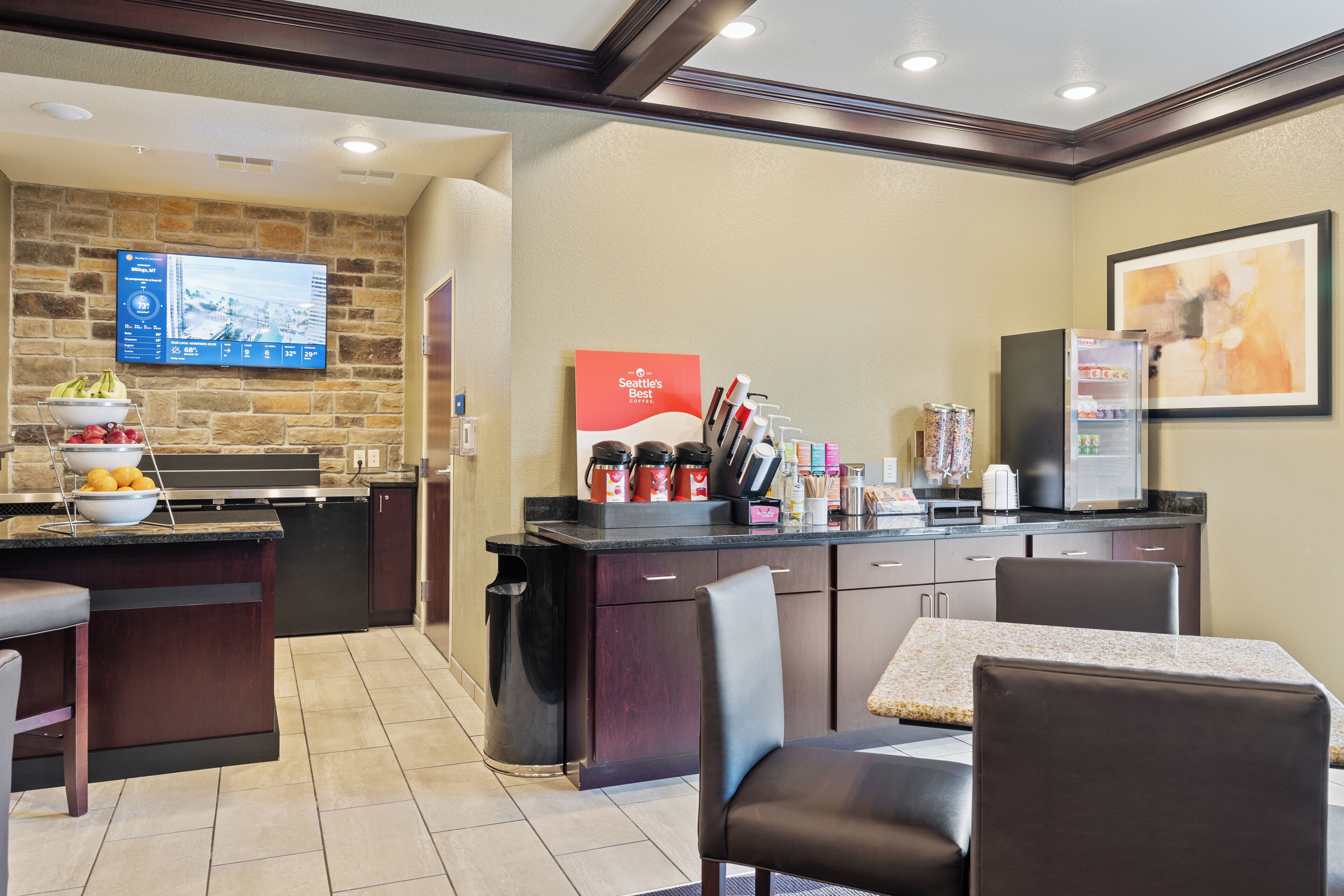 Una cocina moderna con un muro de acento de piedra, un televisor de pantalla plana, una estación de café y un comedor con mesa y sillas.