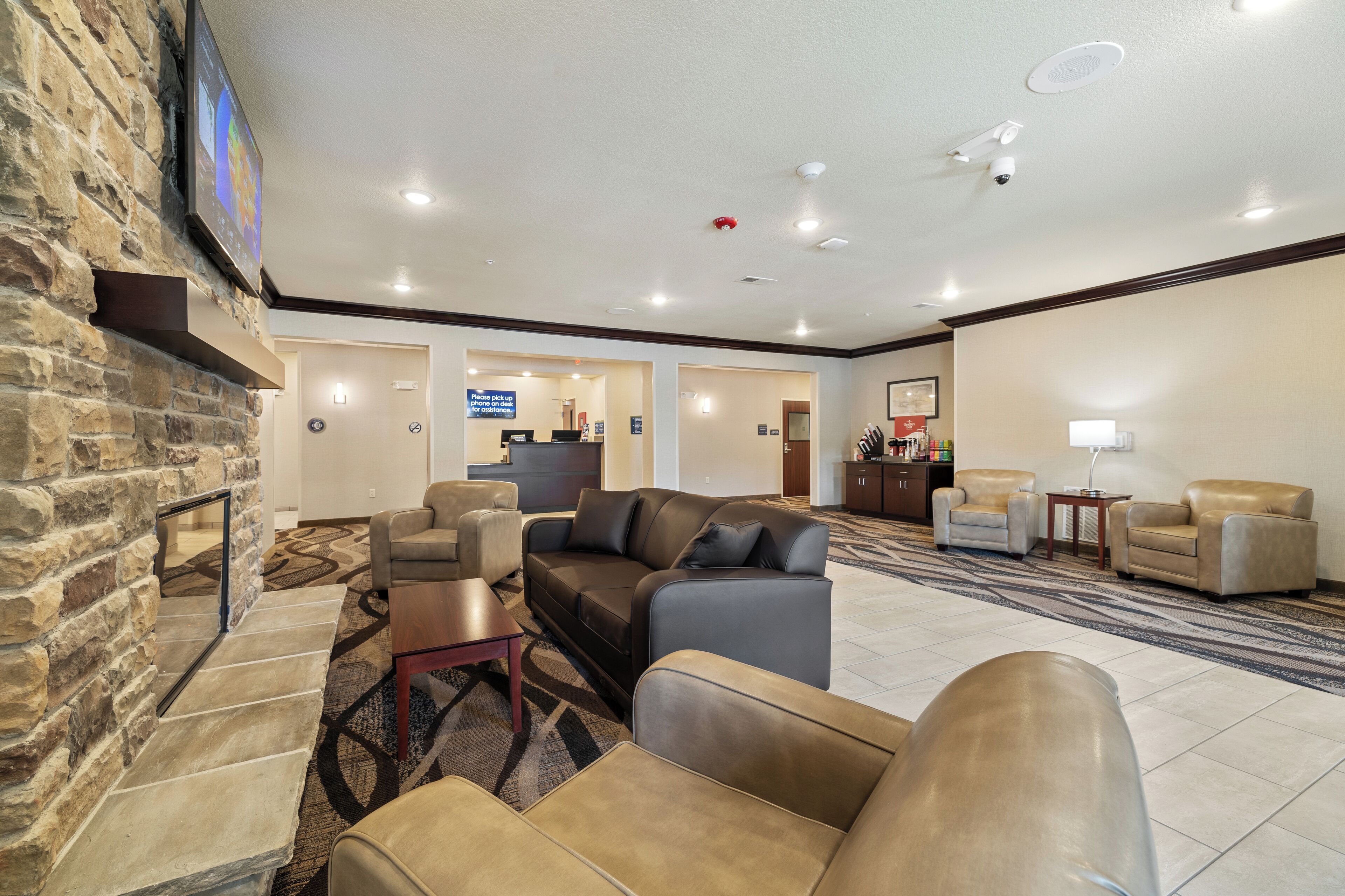 A hotel lobby with a stone wall, a reception desk, leather sofas, and a patterned carpet.