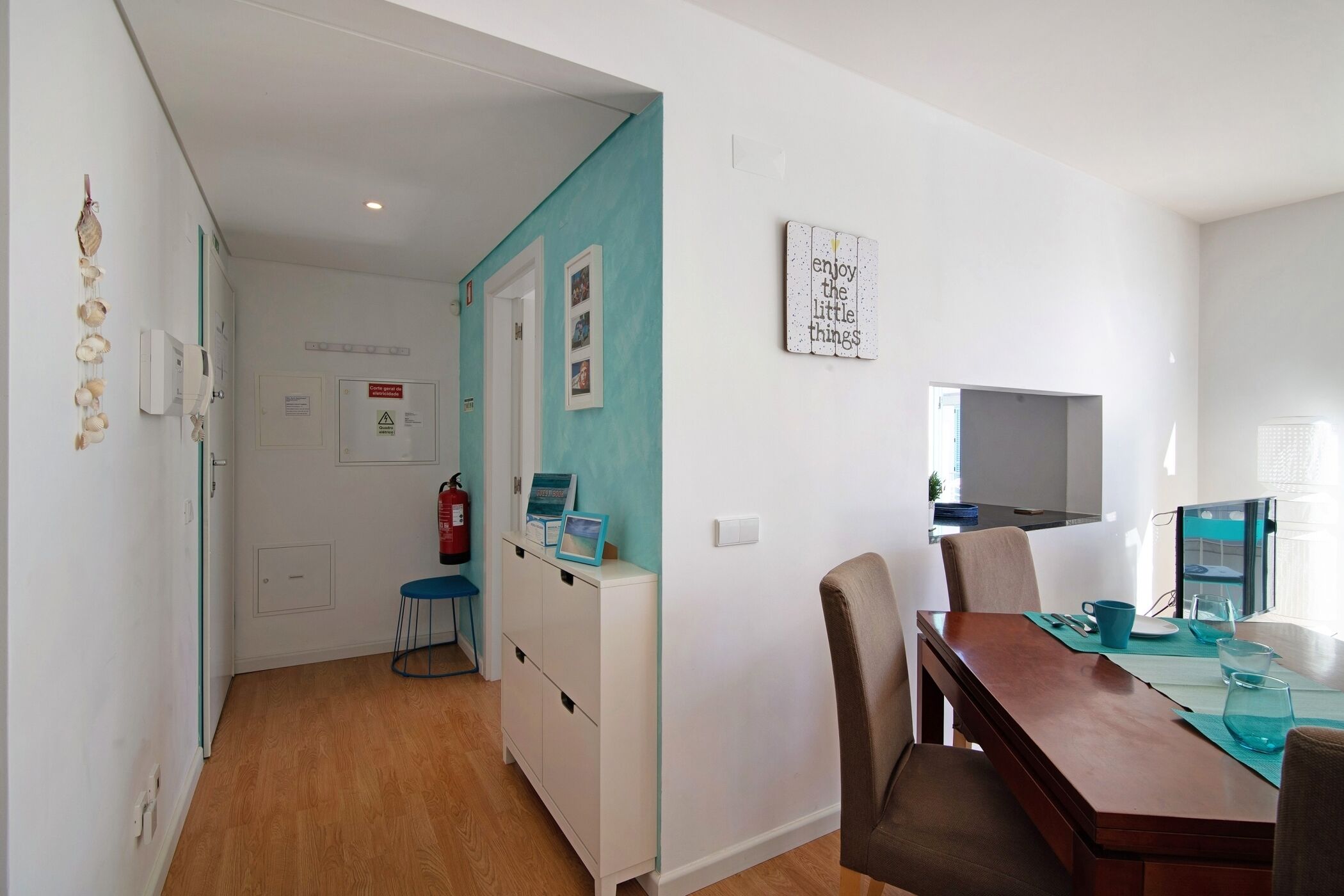 Een moderne keuken met een houten tafel, stoelen en een muur in teal.