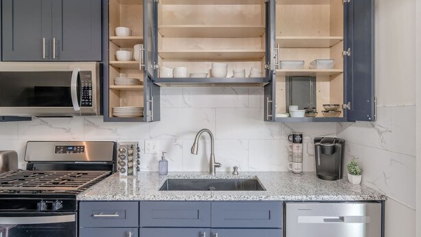A modern kitchen with a built-in microwave, stove, and dishwasher. - Furnished 2BR Retreat with Private Garage (Kansas City)