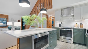 A modern kitchen with a central island, stainless steel appliances, and a mix of green and white cabinetry. - Bryce Resort | Hot Tub | Game Room | Sleeps 12 (Basye)