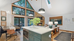 A spacious kitchen with a large island, wooden cabinets, and a stone accent wall. - Bryce Resort | Hot Tub | Game Room | Sleeps 12 (Basye)