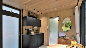 A modern kitchen with black cabinets, a wooden countertop, and a round dining table with a candle and flowers.