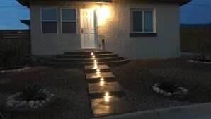 A small, single-story house with a front door and windows, a concrete pathway leading to the door, and a small garden area with rocks and plants. - ⭐️⭐️⭐️La Casita El Paso West side Buena Vista (El Paso)