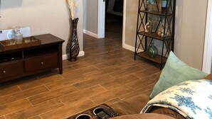 A living room with a TV, a wooden coffee table, a brown leather sofa, and a black shelving unit with decorative items. - ⭐️⭐️⭐️La Casita El Paso West side Buena Vista (El Paso)