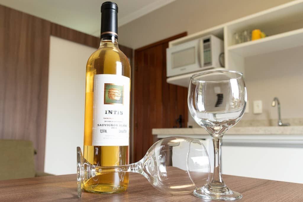 Une bouteille de vin Intis Sauvignon Blanc et un verre à vin sur une table en bois dans une cuisine.