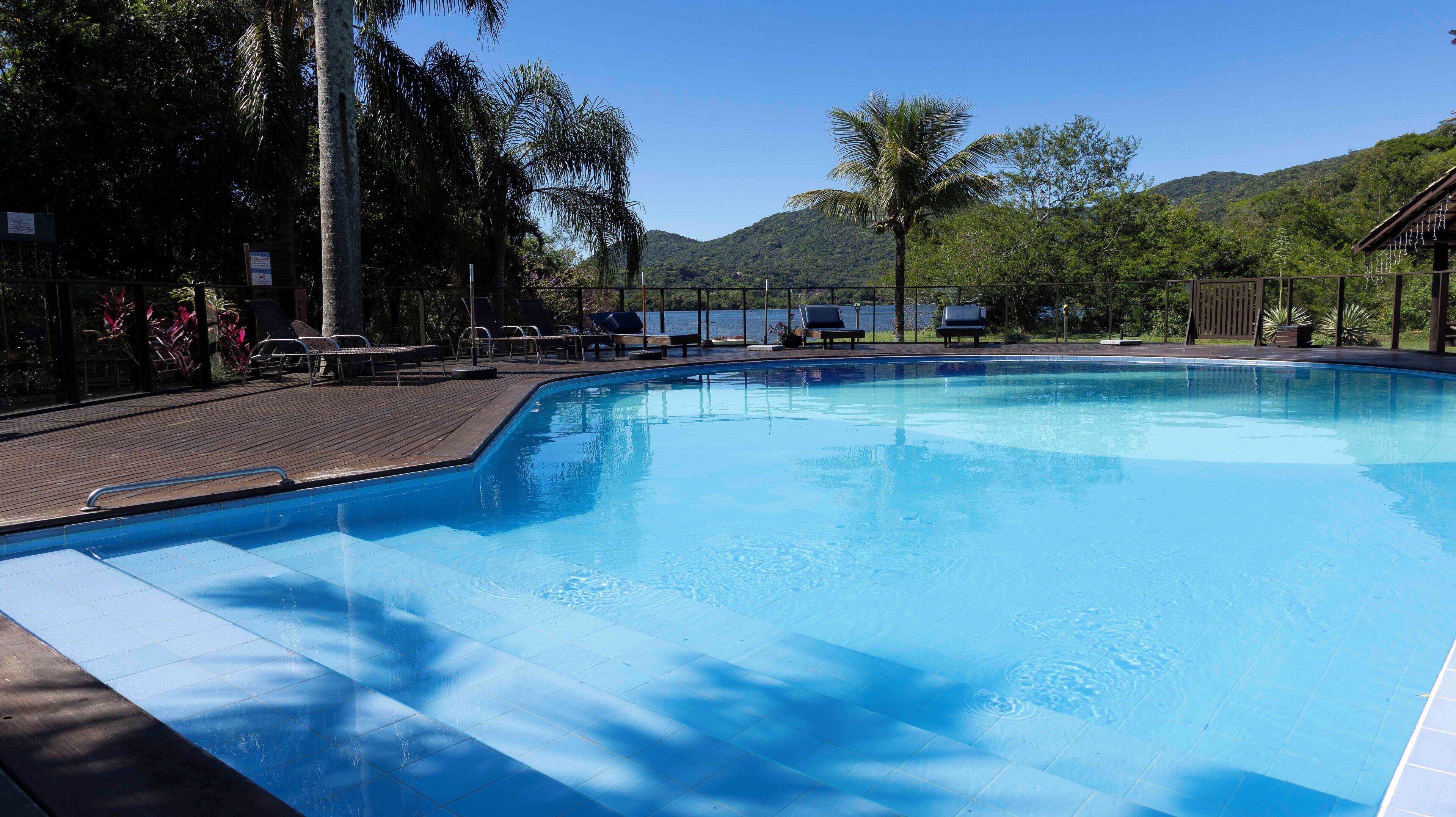A swimming pool with lounge chairs and a view of a lake and mountains.
