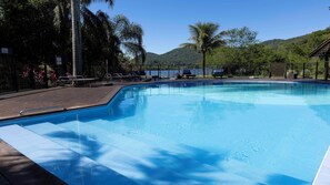 Piscina con sillones de descanso y vistas a un lago y montañas.