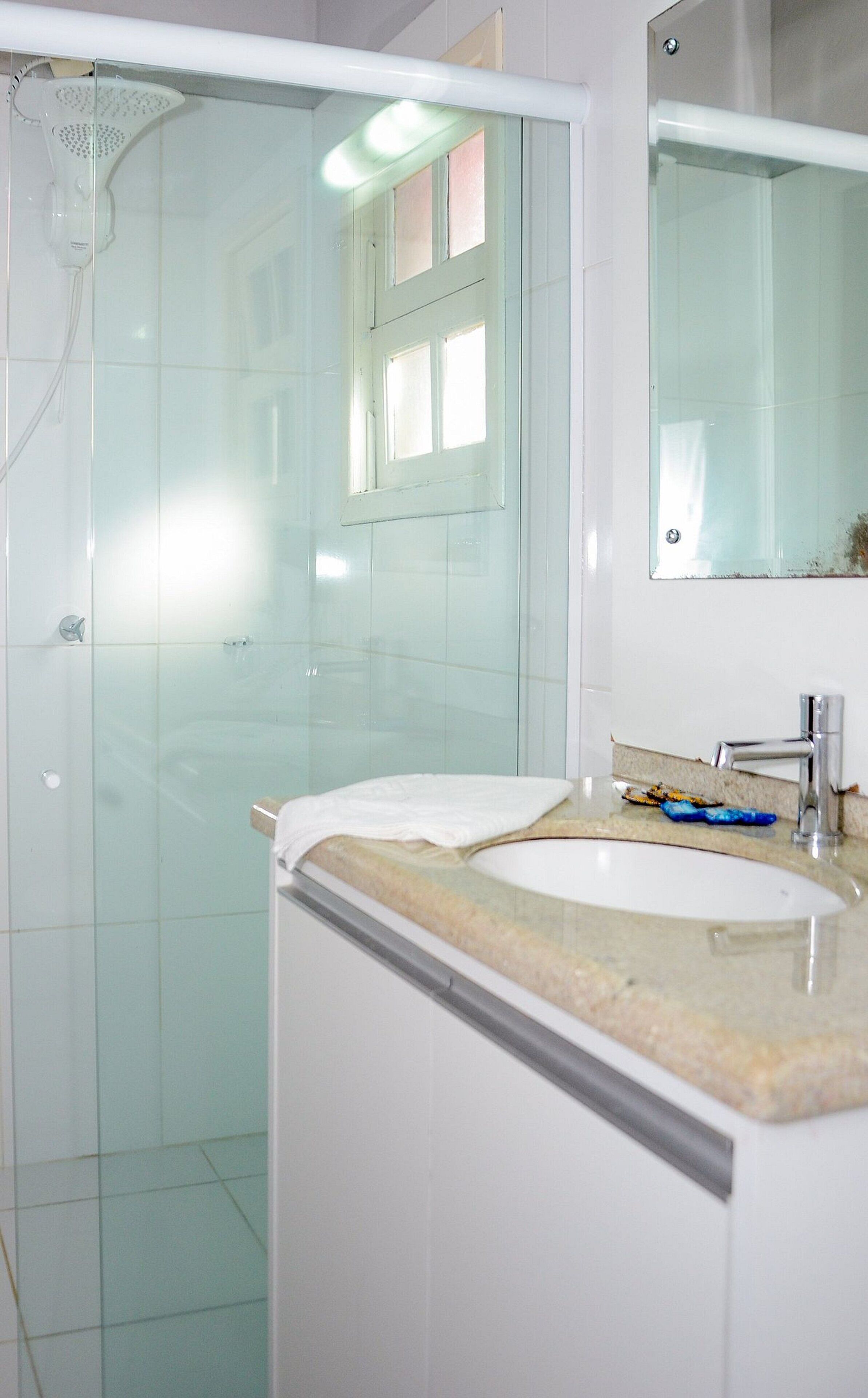 Une salle de bain avec une douche à parois de verre, un lavabo avec un plan de travail et un miroir au-dessus du lavabo.
