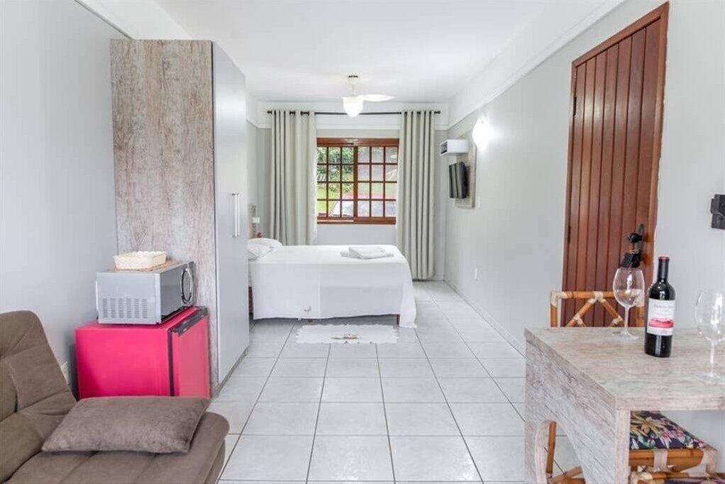 Une chambre d’hôtel avec un lit, une petite table sur laquelle se trouve une bouteille de vin, une chaise et un téléviseur posé sur un meuble.