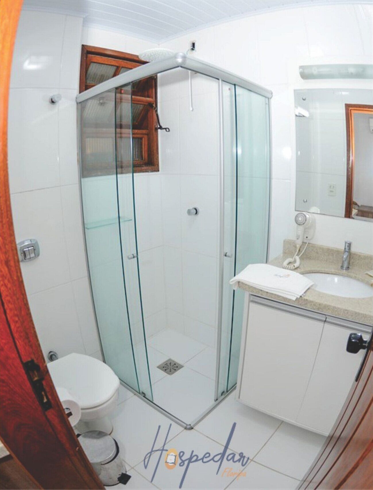 A modern bathroom with a glass shower enclosure, a white toilet, a sink with a vanity, and a mirror above the sink.