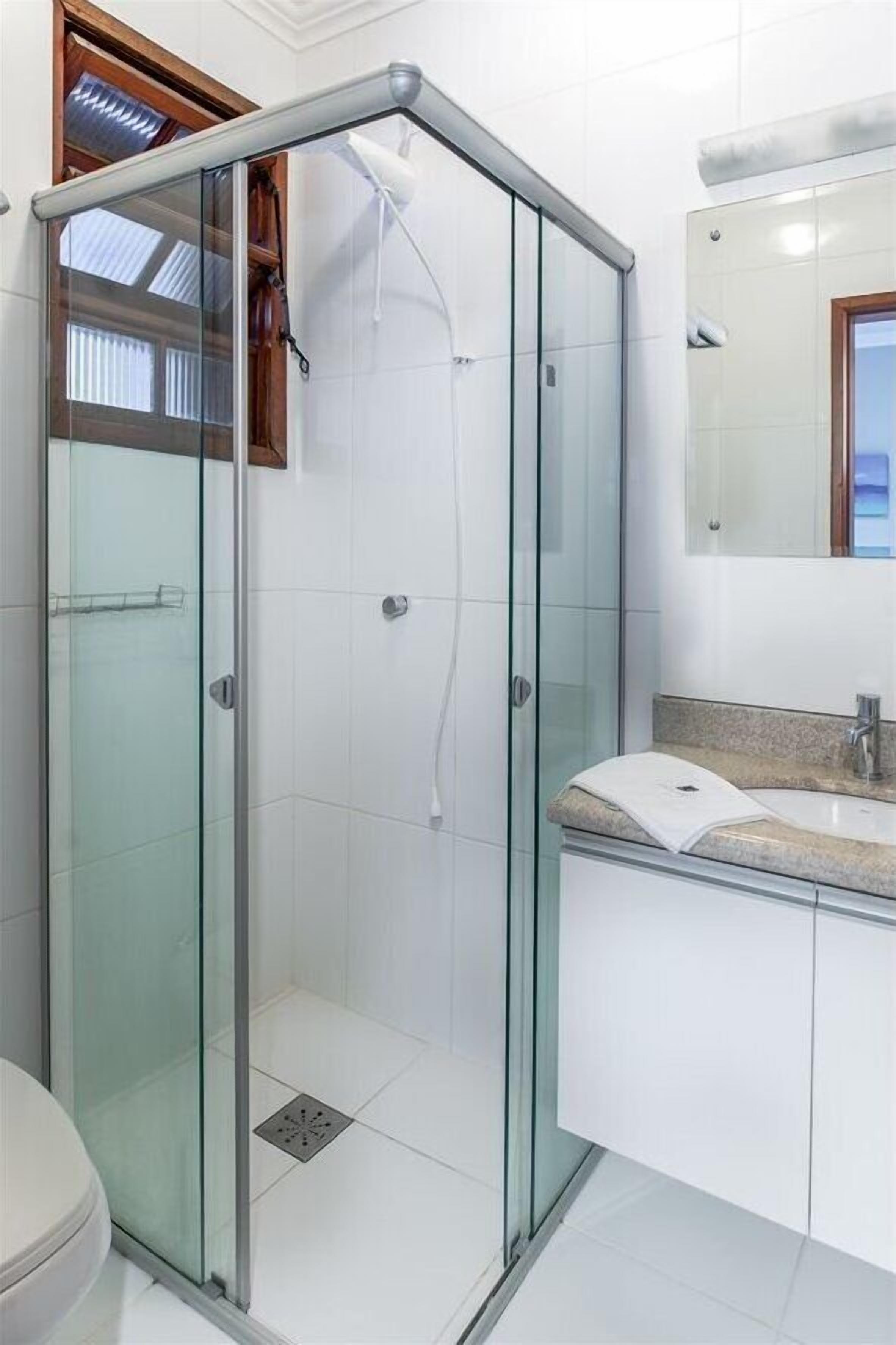 A modern bathroom with a glass shower enclosure, a white sink, and a mirror above the sink.