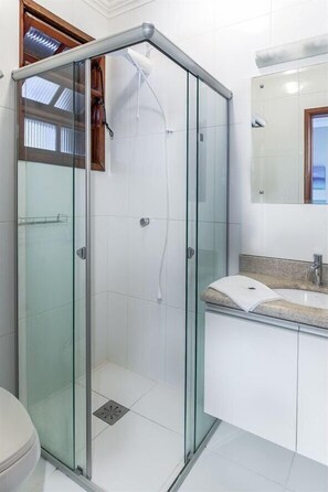 Un baño moderno con cabina de ducha de vidrio, un lavabo blanco y un espejo sobre él.