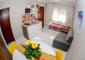 Un espacio habitable compacto con kitchenette, comedor con mesa y sillas, sofá y cama.