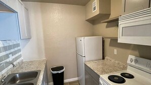 A compact kitchen with a granite countertop, stainless steel sink, white appliances, and a tiled backsplash. - 🤩⭐️fully updated apartment northeast⭐️🤩 (El Paso)