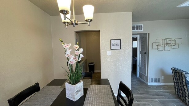 A dining area with a table, chairs, a potted orchid, and a chandelier. - 🤩⭐️fully updated apartment northeast⭐️🤩 (El Paso)