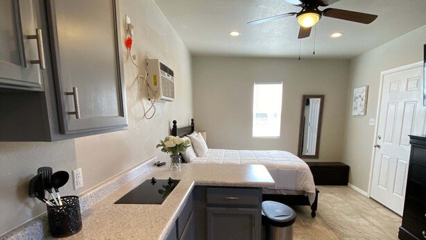 A compact kitchen with a sink, stove, and cabinets, a small trash can, and a ceiling fan. - ⭐️Private stand-alone studio Central⭐️ (El Paso)