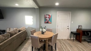 A dining area with a round table, chairs, and a painting on the wall.