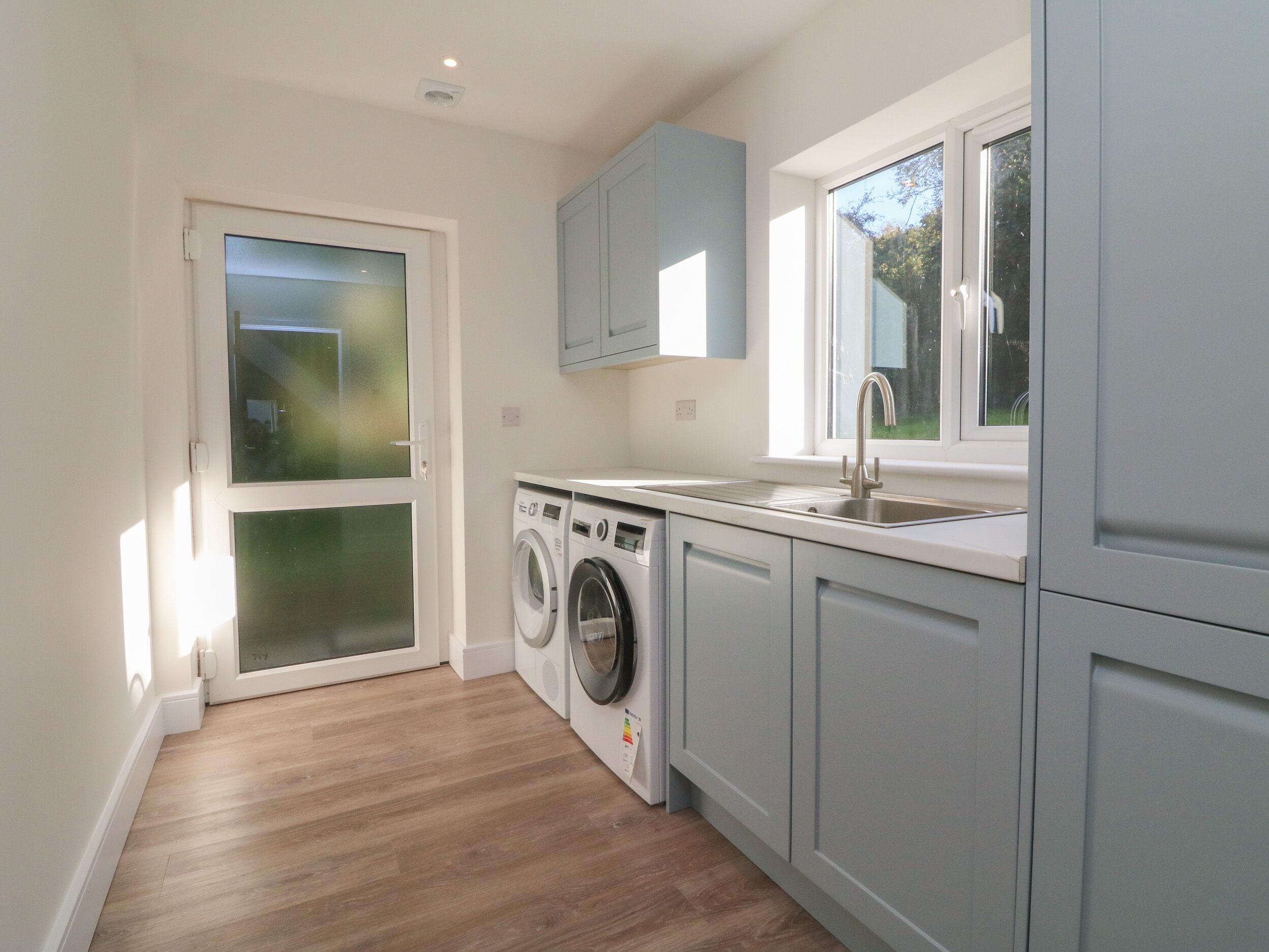 A modern kitchen with a built-in washer and dryer, a sink, and light blue cabinets.