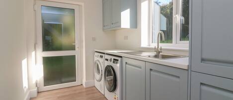 A modern kitchen with a built-in washer and dryer, a sink, and light blue cabinets.