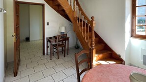A room with a wooden staircase, a dining table with chairs, and a window with a view. - Maison de Campagne Avec vue sur la Chaîne des Pyrénées (VIC-EN-BIGORRE)