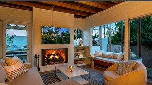 Una sala de estar moderna con chimenea, asientos cómodos y grandes ventanales con vistas al exterior.