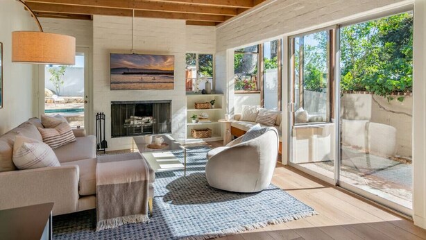 Un salón espacioso con chimenea, asientos cómodos y grandes ventanales que ofrecen vistas al exterior.