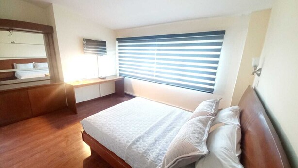 Un dormitorio con cama, escritorio y ventana con persianas.