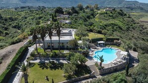 Eine Villa mit Swimmingpool, umgeben von üppiger Vegetation und einer Bergkulisse.