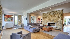 Ein geräumiges Wohnzimmer mit Steinwand, Kamin und einem großen abstrakten Gemälde.