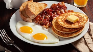 A breakfast plate with eggs, bacon, toast, and pancakes. - Lasuiza Suites (San Bernardino)