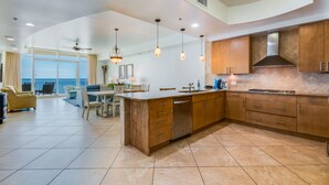 A spacious kitchen with a large island, wooden cabinets, and a view of the ocean.