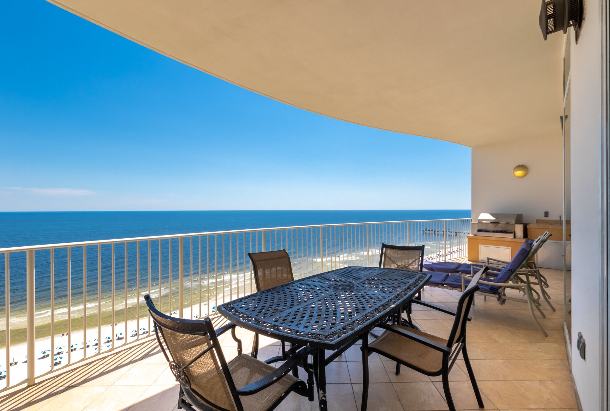 A balcony with a table and chairs, overlooking the ocean.