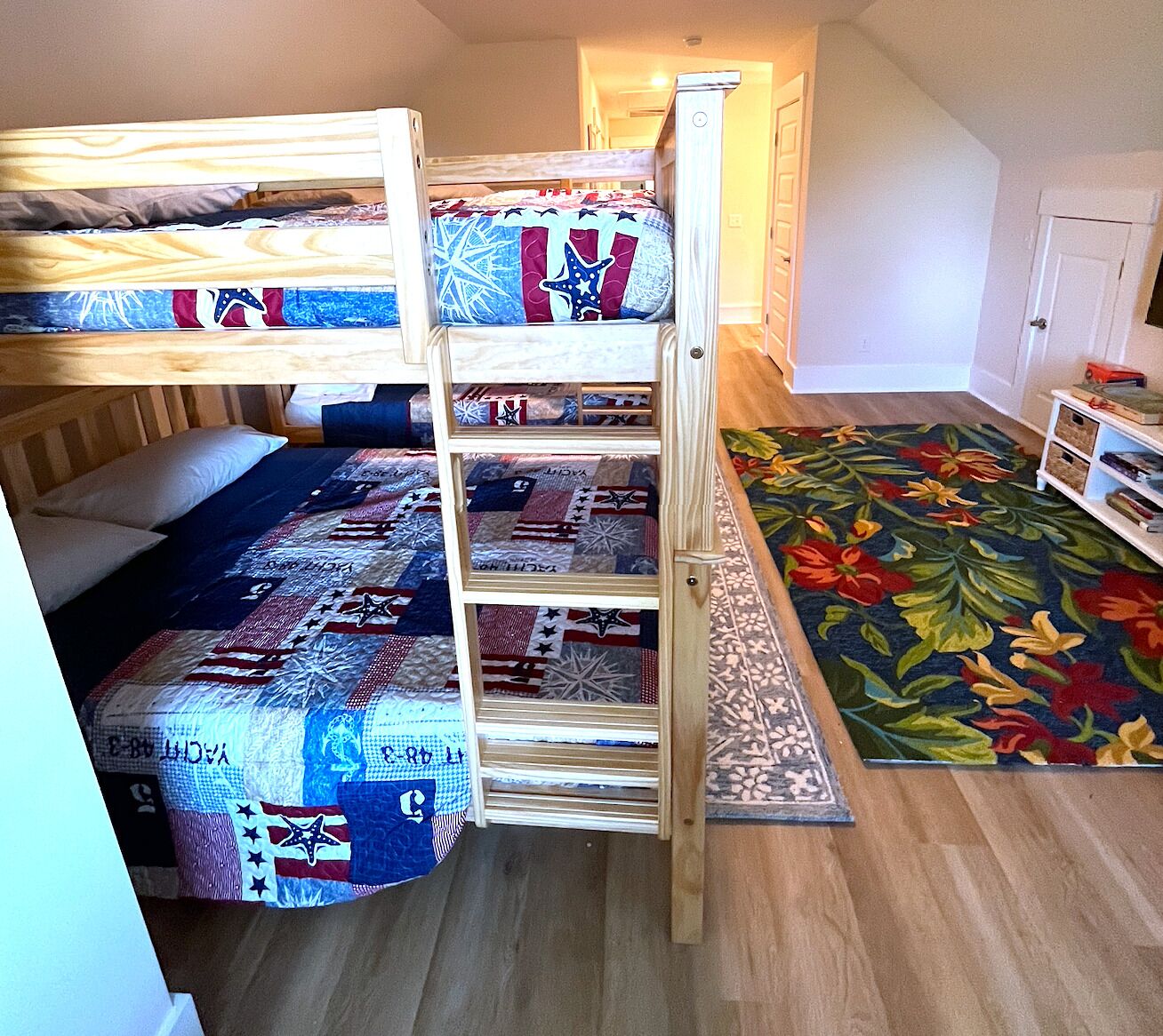 Een slaapkamer met een stapelbed, een kleurrijk vloerkleed en een klein tafeltje met boeken.