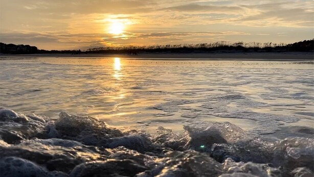Un llac gelat amb el sol reflectint sobre la superfície.