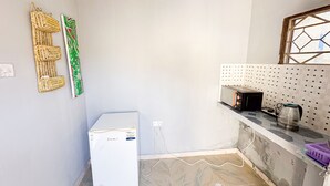 A compact kitchen with a refrigerator, a kettle, and a small sink. - Mama's House (Zanzibar Town)