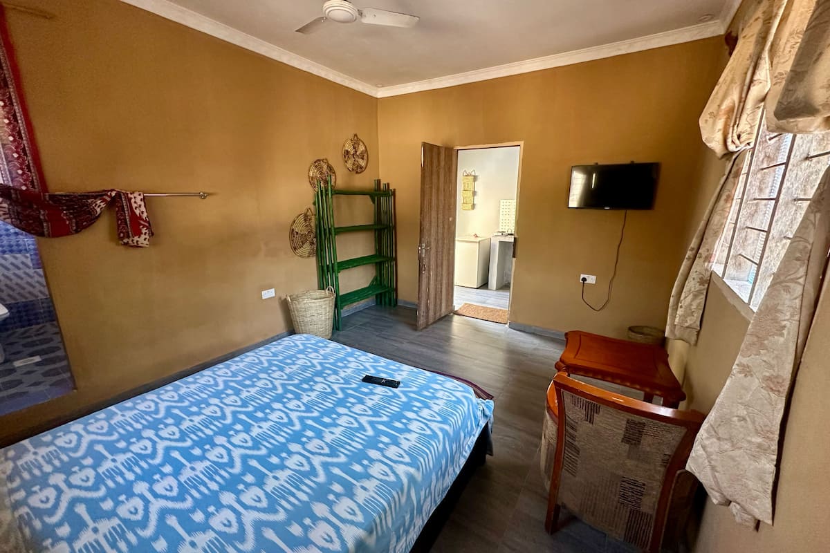 A bedroom with a bed, a desk, a television, and a wardrobe.