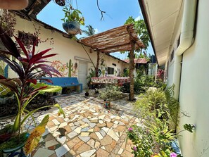 A courtyard with a mosaic floor, a blue bench, a hanging plant, and a wooden pergola. - Mama's House (Zanzibar Town)