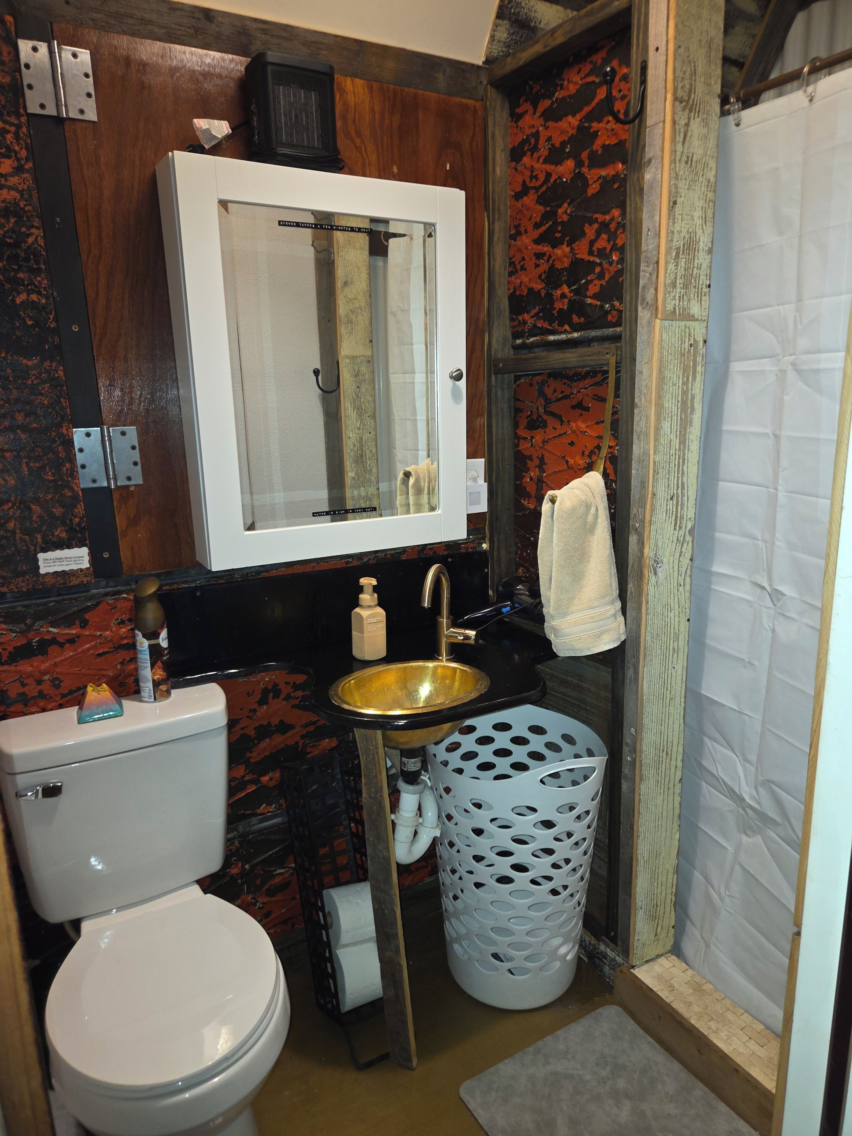 A bathroom with a toilet, sink, mirror, and shower curtain.