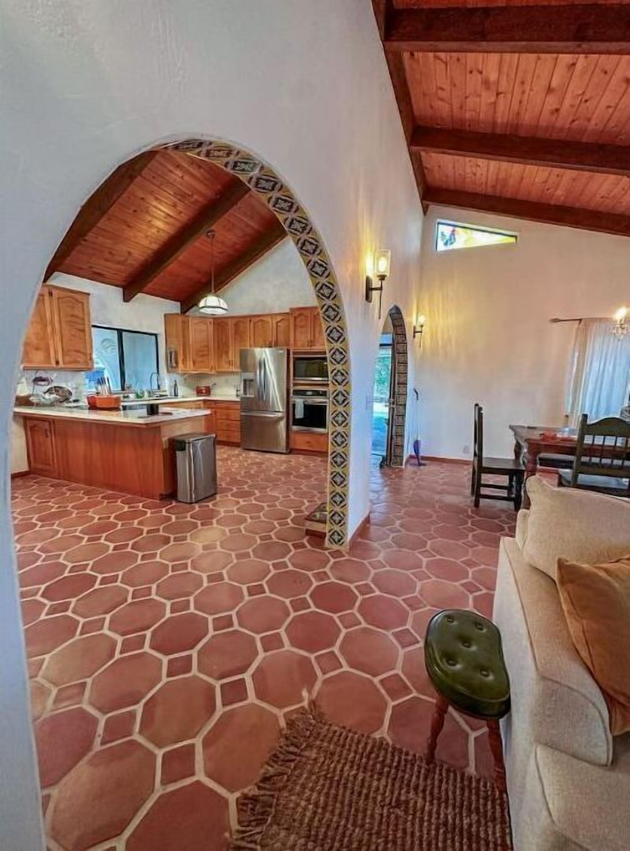 A spacious kitchen with wooden cabinets, a central island, and a stone-patterned floor.