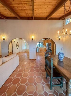 Un ambiente spazioso con pavimento in pietra, travi a vista in legno e zona pranzo con tavolo e sedie in legno.