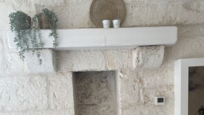 A rustic stone wall with a white shelf holding plants and a woven basket.