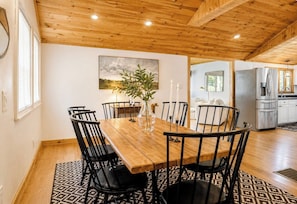 A dining area with a wooden table and chairs, a vase with candles, and a painting on the wall.