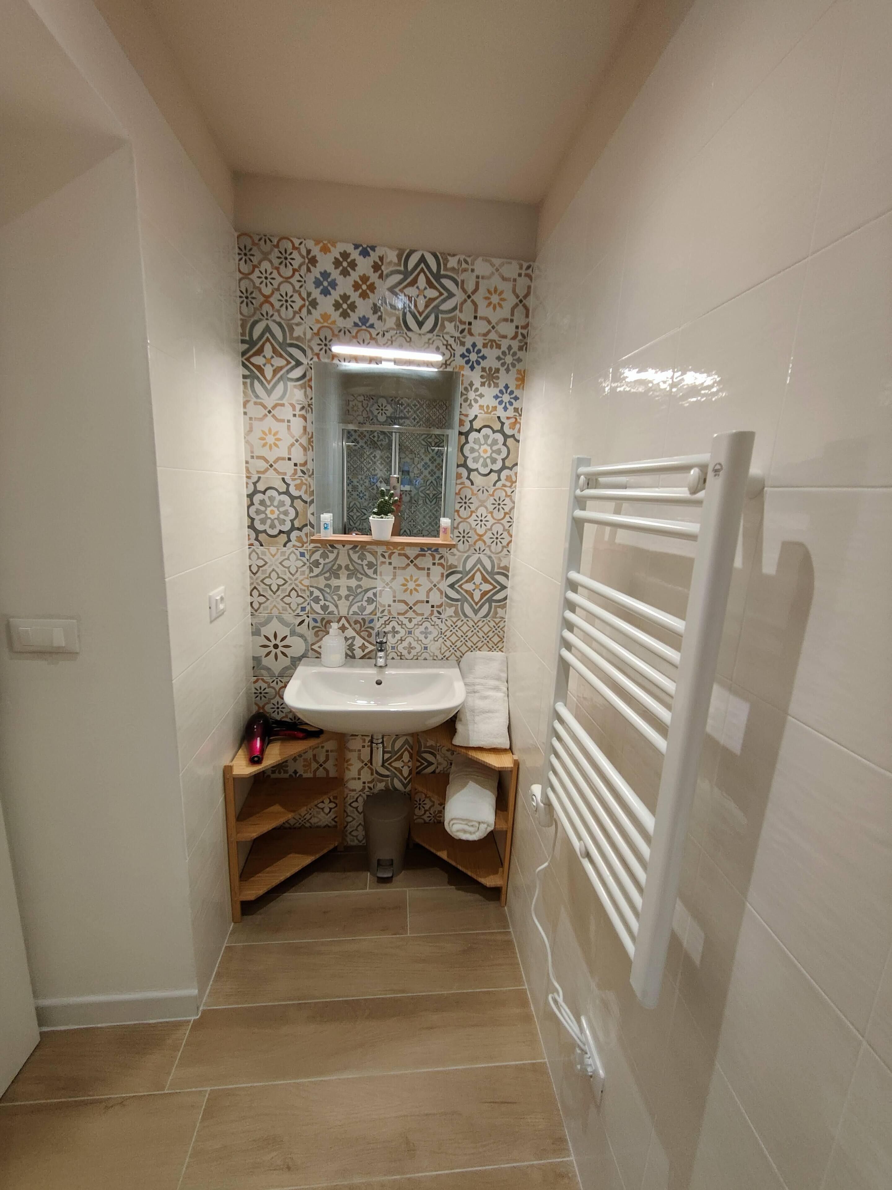 A small bathroom with a sink, mirror, and towel rack.