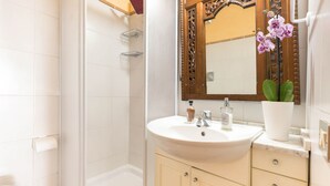 Un baño con lavamanos blanco, espejo, inodoro y ducha.