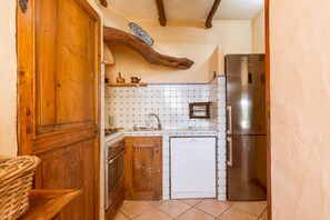 Una cocina compacta con un armario de madera, un lavavajillas blanco y un refrigerador de acero inoxidable.