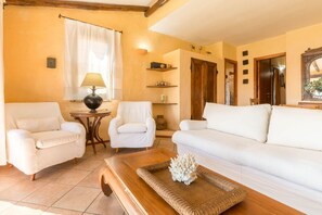 A living room with two white sofas, a wooden coffee table, and a lamp. - LUNA BAY HOME RETREAT with a view of Porto Luna Bay, 2 km from Villasimius (VILLASIMIUS)