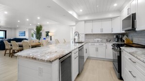 A modern kitchen with white cabinetry, a marble countertop, and a built-in dishwasher.